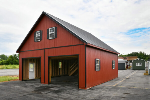 Two-story two-car garage with peak roof and red siding with dark trim